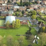 Aerial view of Shrewsbury High School campus in Shropshire showing classrooms, tennis courts, sports field, and surrounding residential area.