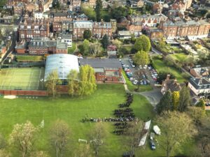Aerial view of Shrewsbury High School campus in Shropshire showing classrooms, tennis courts, sports field, and surrounding residential area.